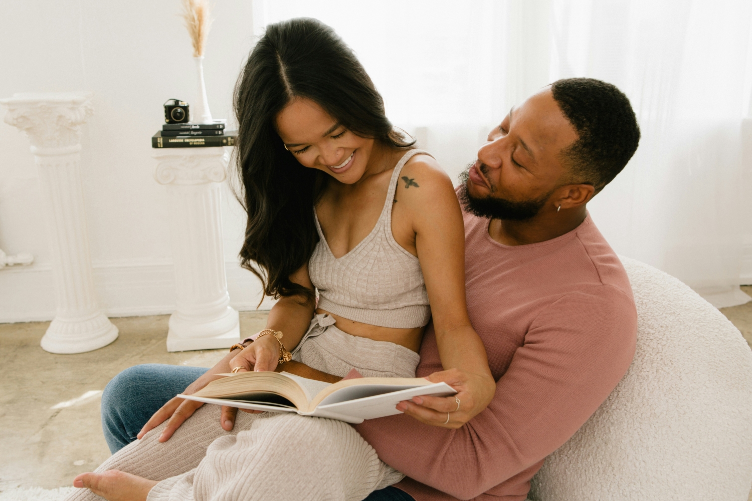 Couple relaxing at home reading a book together; working through financial questions to ask before marriage, one topic at a time